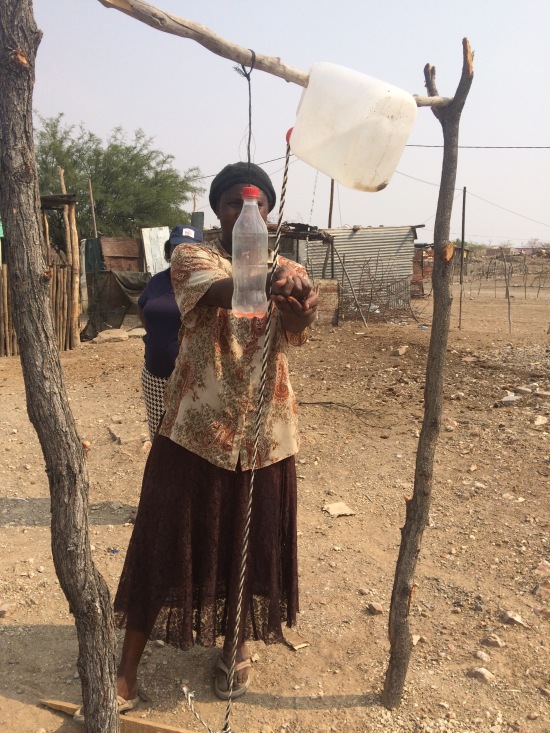 One of the women who had a Tippy-Tap built in her yard, demonstrating the hand washing techniques that the HEWs taught her. She was so proud to be able to teach others in her community and happy that her children would get cleaner food now.